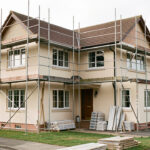Maison individuelle en rénovation extérieure avec façade échafaudée, toiture et fenêtres visibles sous une lumière naturelle.