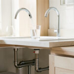 Qualité de l’eau à la maison : 7 équipements et gestes utiles Cuisine lumineuse et moderne avec robinet chromé, verre d’eau, filtre discret sous l’évier et plomberie propre.