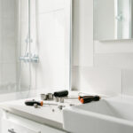Protéger sa maison du calcaire : les gestes et solutions durables Salle de bains lumineuse avec robinet chromé, paroi de douche en verre et outils de plomberie soigneusement disposés.
